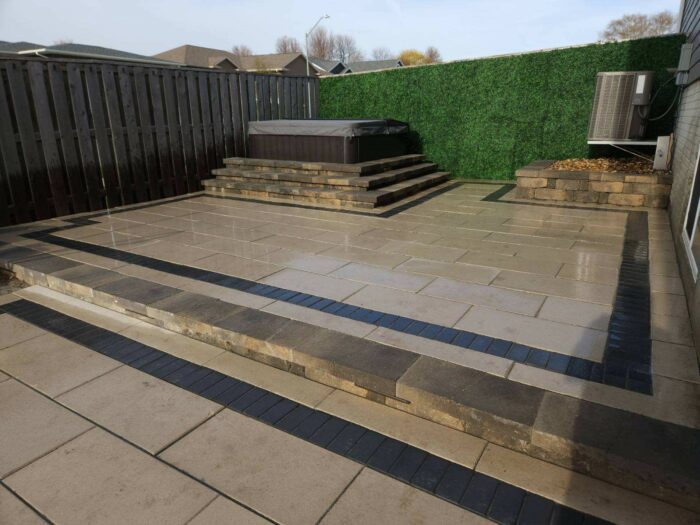 Hot tub patio with lighting and steps up to hot tub after photo of paver patio with raised steps to hot tub landscaping project